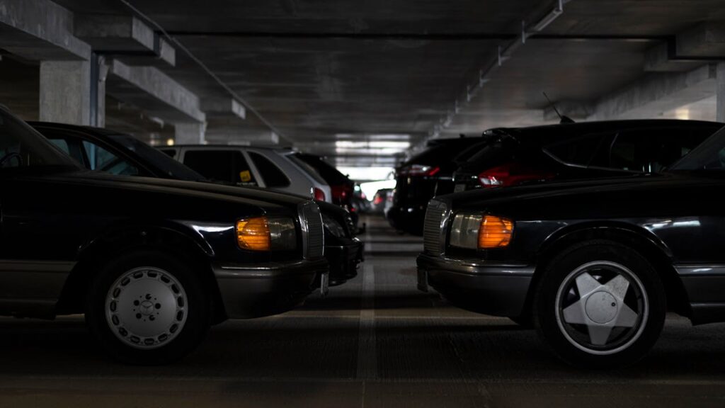 Classic cars parked in an indoor parking garage with muted lighting.